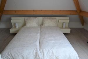 a large white bed with two pillows in a room at Vakantiewoning aan duinen en zee in Dishoek in Dishoek +6 photos