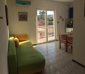 a living room with a green couch and a table at Lipovac resort Ficus in Bilice