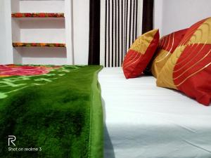 カジュラーホーにあるKhajuraho Dreams Homestayの赤と緑のシーツと枕が備わるベッド
