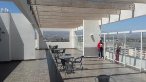 a woman standing on a balcony with tables and chairs at La Serena Mini Departamento in La Serena