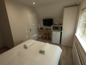 a small room with a bed and a kitchen at Debden Guest House in Hillingdon