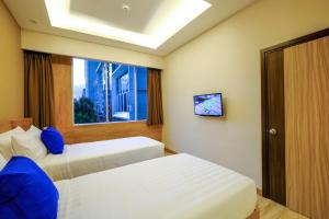 a hotel room with two beds and a window at Desatu Hotel in Medan