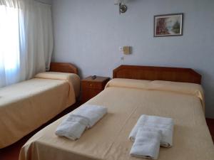 una camera da letto con due letti con asciugamani sopra di Hotel Frasi's a San Clemente del Tuyú