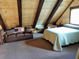 Freedom Ridge Cabins في هيل سيتي: غرفة نوم بسرير واريكة في غرفة