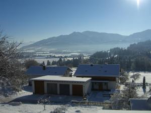 a house in the snow with mountains in the background at Gästehaus Eckstein in Oy-Mittelberg