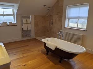 a bath tub sitting in a bathroom next to a window at Elderbrook House in Avebury