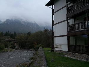 a building next to a river next to a mountain at APARTAMENT GOLDEN ROSE 2 in Buşteni