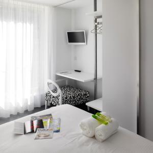 a white bedroom with a bed with a desk at Moure Hotel in Santiago de Compostela