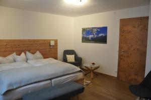 ein Schlafzimmer mit einem Bett, einem Stuhl und einer Tür in der Unterkunft Gästehaus Mayer in Mieming