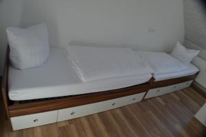 ein Bett mit weißer Bettwäsche und Kissen darauf in der Unterkunft Ferienwohnung im Alten Zollhaus in Kurort Oberwiesenthal