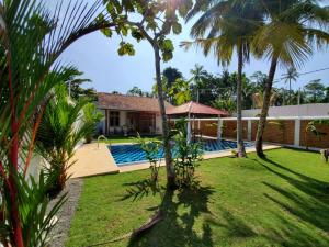 a house with a swimming pool and palm trees at The Rock Villas in Ahangama