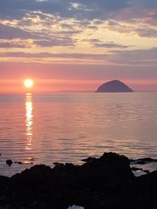 zachód słońca nad oceanem z górą w oddali w obiekcie Clach Mhor w mieście Girvan