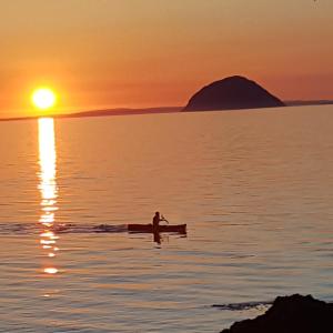 osoba w łodzi w wodzie o zachodzie słońca w obiekcie Clach Mhor w mieście Girvan