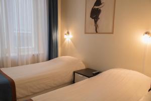 een hotelkamer met 2 bedden en een raam bij Hotel Doria in Amsterdam