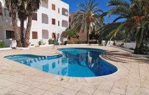 - une piscine en face d'un bâtiment avec des palmiers dans l'établissement Apartamentos CostaMar 1; Apartamento nº11, à Es Pujols