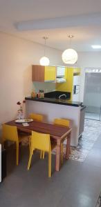 cocina con mesa de madera y sillas amarillas en Ondas da Guarda Moradas, en Guarda do Embaú