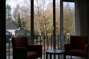 2 chaises et une table devant une fenêtre dans l'établissement Hotel Duinrand Drunen, à Drunen