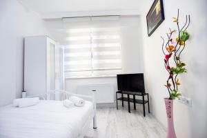 a white room with a bed and a vase with flowers at Arney Suites in Eskisehir