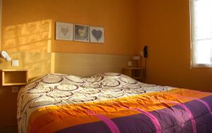 a bedroom with a bed with a colorful blanket at Hôtel de Tessé in Bagnoles de l'Orne