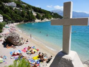 a cross on a beach with people on the beach at Mimice Bay Apartments in Mimice