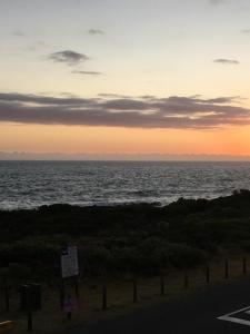 uma vista para o oceano ao pôr-do-sol a partir de uma estrada em Bungalow by the sea near Cape Town em Kleinmond