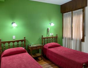 two beds in a room with green walls at Hotel Villa Inés Mendoza in Mendoza