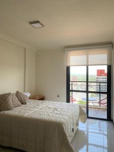 1 dormitorio con 1 cama grande y balcón en Departamento céntrico con increíble vista panorámica en Villa Carlos Paz