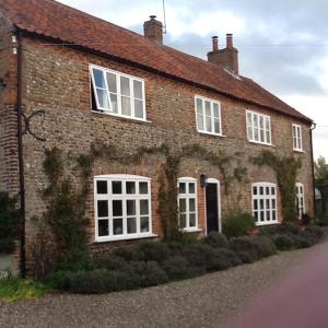 una casa de ladrillo con ventanas blancas en una calle en Garwood House, en Holt