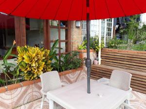 une table avec un parapluie rouge et deux chaises dans l'établissement El Portal de Mariana, à Pereira