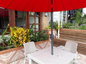 a table with a red umbrella and two chairs at El Portal de Mariana in Pereira