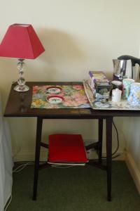 a table with a lamp and a red chair at Garwood House in Holt