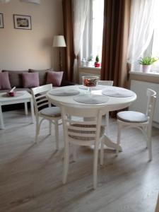 - une table et des chaises blanches dans le salon dans l'établissement come&stay Zielona Góra, à Zielona Góra