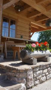 a porch of a wooden cabin with flowers on it at Urlaub am Bauernhof Höbarten in Sankt Anton an der Jessnitz