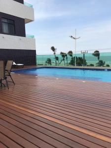 a wooden deck with a swimming pool in front of a building at Litorânea Praia Hotel in São Luís