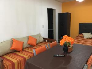 - un salon avec un canapé et une table avec des oreillers orange dans l'établissement El VIEJI, à Colón