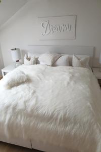 Cama blanca con sábanas y almohadas blancas en Haus Sonnenschein, en Lam