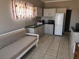 a kitchen with a couch and a white refrigerator at Kom Kuier Self-Cater in Vredenburg