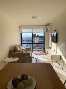 una sala de estar con una mesa y una mujer mirando por la ventana en Departamento céntrico con increíble vista panorámica en Villa Carlos Paz