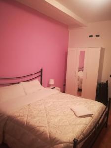 een slaapkamer met een bed met een roze muur bij B&B Ciampino in Ciampino