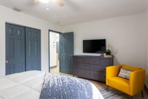 a bedroom with a bed and a tv and a yellow chair at Casa Madeira @ the heart of Miami Design District in Miami