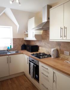 une cuisine avec des armoires blanches et un four à plaques de cuisson dans l'établissement YBC Court, Aldershot, à Aldershot