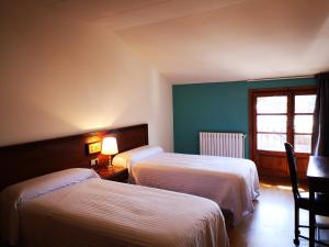 a hotel room with two beds and a window at Hotel Santa Bàrbara De La Vall D'ordino in Ordino