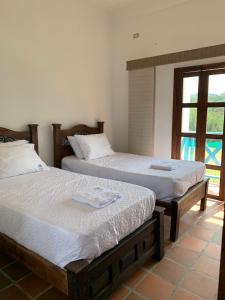 two beds sitting in a room with a window at Hotel la hacienda del pienta in Charalá