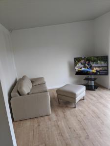 a living room with a couch and a tv at Ferienhaus Schieferterrasse - Waldsee Rieden - in Rieden