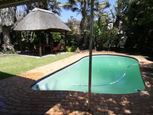 een zwembad in een tuin met een parasol bij Versailles B and B in Gonubie