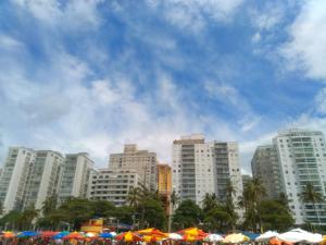 um grupo de edifícios e guarda-chuvas em frente a uma cidade em Flat Praia Pitangueiras no Guarujá