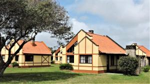 una casa con techo naranja y un árbol en Country del Sol Complejo Turistico en La Paloma