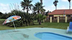 a umbrella in a yard next to a swimming pool at Country del Sol Complejo Turistico in La Paloma