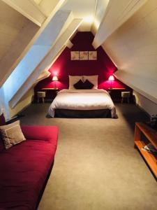 Dormitorio en el ático con cama y sofá rojo en la linoterie, en Colembert