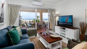 a living room with a blue couch and a tv at Illovo Beach Apartments at La Mer in Amanzimtoti